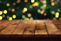 a wooden table with a blurry christmas tree in the background with lights on it and a green boke of lights