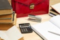 On a wooden table books, documents, calculator, red briefcase. Royalty Free Stock Photo