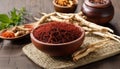A wooden table with a bowl of red spices and a pile of dried herbs