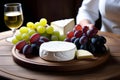 Still life of a wooden table with a variety of cheeses, grapes, and wine Royalty Free Stock Photo