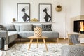 Wooden table on carpet in african living room interior with patterned cushions on grey sofa. Real photo