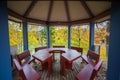 a wooden table and chairs on a deck with a view of trees and a lake in the background with a gazebo