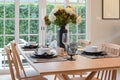 Wooden table and chairs in dining room with elegant table setting Royalty Free Stock Photo