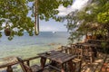 Wooden table and chairs in empty beach cafe next to sea water. Island Koh Phangan, Thailand Royalty Free Stock Photo