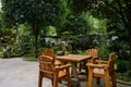 Wooden table and chairs in verdant yard on summer day