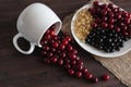 On a wooden table are cherries, white and black currants in a white porcelain mug and plate Royalty Free Stock Photo