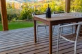 relaxing moment, wooden table with bottle of chilled wine in the green garden of a luxury home