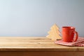 Wooden table with coffee cup and wooden Christmas tree over gray wall background. Christmas and New Year mock up for design and