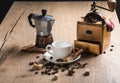 On the wooden table is a coffee maker mocha, vintage coffee grinder. White saucer with a cup are cinnamon sticks. Coffee Royalty Free Stock Photo