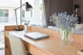 Wooden table with computer notebook,pencil,lamp and flowers in modern working area