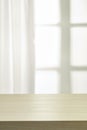 Wooden table on defocuced window with curtain