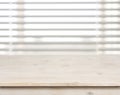 Wooden table on defocuced window with venetian blinds background