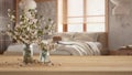 Wooden table, desk or shelf close up with branches of cherry blossoms in glass vase over wooden bedroom with double bed, japandi