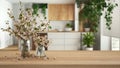 Wooden table, desk or shelf close up with branches of cherry blossoms in glass vase over blurred view of minimal kitchen and