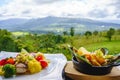 Wooden table with a dish of fish fillet and a plate of marinated mussels in front of a forest landscape