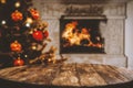 Wooden table with empty space for products and decorations. Blurred fireplace and christmas tree interior background. Royalty Free Stock Photo