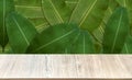 A wooden table in front, the background is a green banana leaf arranged like a wall