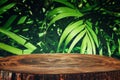 Wooden table in front of tropical green tropical floral background. for product display and presentation Royalty Free Stock Photo