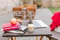 Wooden table with a glass of milk shake, red apple and white computer. Daily newspapers and books next to morning latte Royalty Free Stock Photo