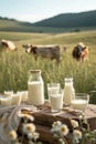 A wooden table with glasses and bottles filled with fresh milk. In the background, a pastoral landscape, complete with a herd of