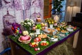 A wooden table with a grassy tablecloth and Easter treats: eggs, cakes, chocolate eggs, meringues