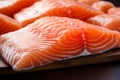 Wooden table hosts a close up of fresh, raw salmon fillets
