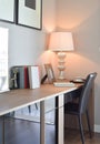 Wooden table with lamp and books in modern working room interior