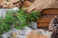 On a wooden table lie coarse gray fabrics, on top of a green pine branch with long needles, a handful of peeled pine