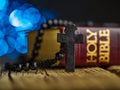 On a wooden table lies a red book - the Holy Bible and a rosary with a cross on a dark blue background. Jesus Christ, holy Royalty Free Stock Photo