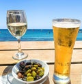 Wooden table with light beer in the mug , white wine in the glass and olives in white plate Royalty Free Stock Photo