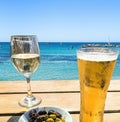 Wooden table with light beer in the mug , white wine in the glass and olives in white plate Royalty Free Stock Photo