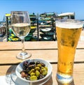 Wooden table with light beer in the mug , white wine in the glass and olives in white plate