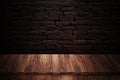 Wooden table made with natural wood planks with a concrete block wall background in a dark room Royalty Free Stock Photo