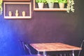 Wooden table with metal chairs placed close to the wall in coffee shop, on the wall has cute decoration of artificial plants and Royalty Free Stock Photo