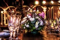 Wooden table mounted with plates and fine glasses for a reseption, adorned with flowers and lights in a hacienda