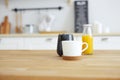 Wooden table with mug, milk jug and orange juice with blurred kitchen background Royalty Free Stock Photo