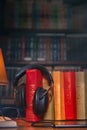 On a wooden table next to the lamp are headphones, a phone, a stack of books and glasses. The concept of modern technology and Royalty Free Stock Photo