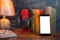 On a wooden table next to the lamp are headphones, a phone, a stack of books and glasses. The concept of modern technology and Royalty Free Stock Photo