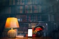 On a wooden table next to the lamp are headphones, a phone, a stack of books and glasses. The concept of modern technology and Royalty Free Stock Photo