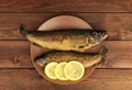 On the wooden table is a plate with two baked fish Royalty Free Stock Photo