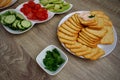 Wooden table with plates with chopped vegetables and crackers. Quick and healthy snacks. Buffet. Lots of fresh vegetables. Cheese