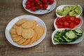 Wooden table with plates with chopped vegetables and crackers. Quick and healthy snacks. Buffet. Lots of fresh vegetables. Cheese