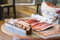 Wooden table with raw ham sliced packed with ham leg in the background