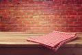 Wooden table with red checked tablecloth over brick wall