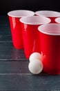 Wooden table with red cups and ball for beer pong Royalty Free Stock Photo