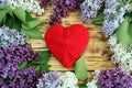 On a wooden table are several branches of lilac and in the middle a red heart Royalty Free Stock Photo