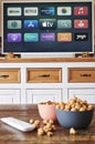 Wooden table with snacks, remote control and a TV