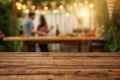 wooden table space with a blurred couple decorating a bbq party scene behind Royalty Free Stock Photo