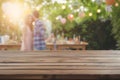 wooden table space with a blurred couple decorating a bbq party scene behind Royalty Free Stock Photo