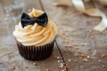 On a wooden table, a special cupcake and bow tie are displayed in celebration of Father's Day